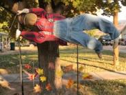 Scarecrow hanging horizontally from a light post. 