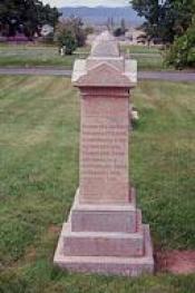 Tall pointed brick colored cemetery stone.
