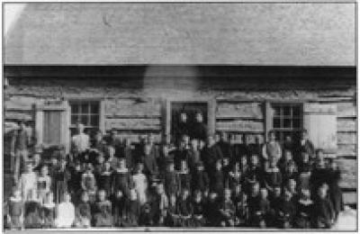 Historical photo of people in front of the original log council hall