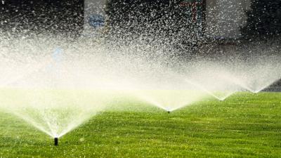 A picture of sprinklers spraying a green lawn